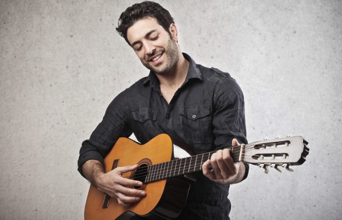 man playing the guitar on a grey background