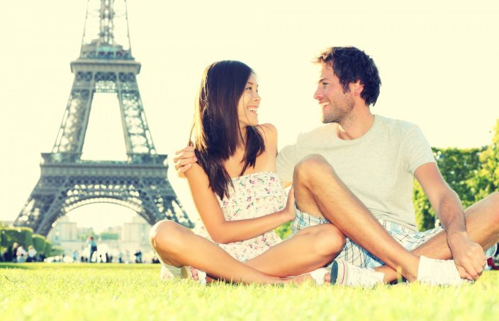 man and woman sitting in front of the eiffel tower