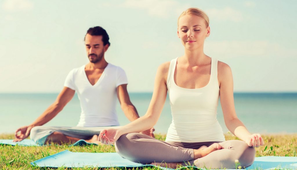 man and woman doing yoga outside 