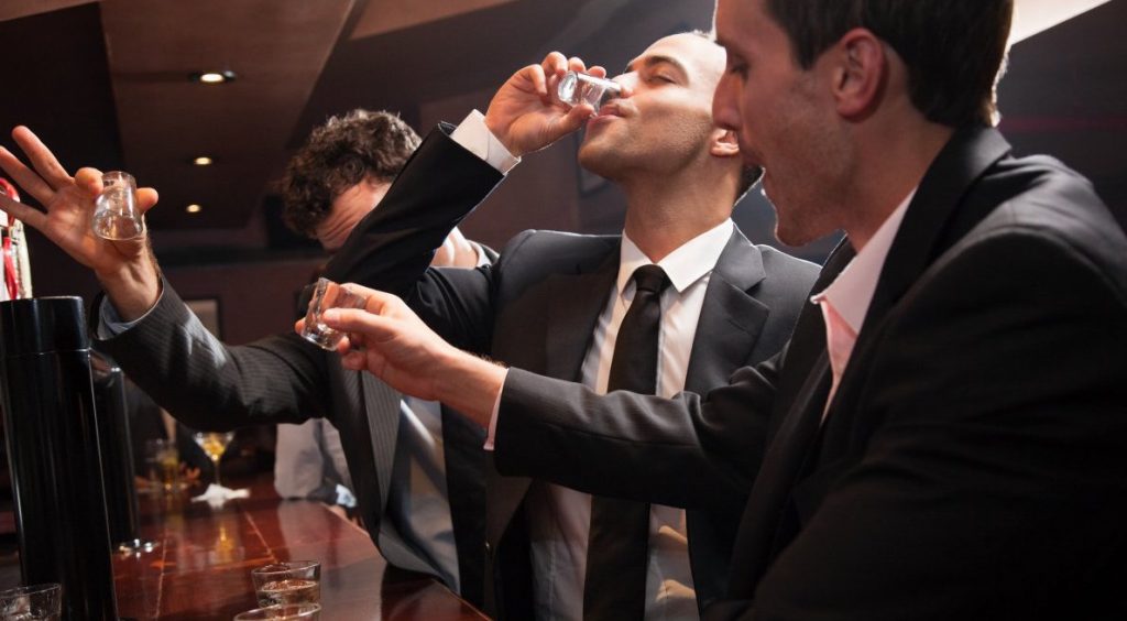 men drinking and taking shots at the bar