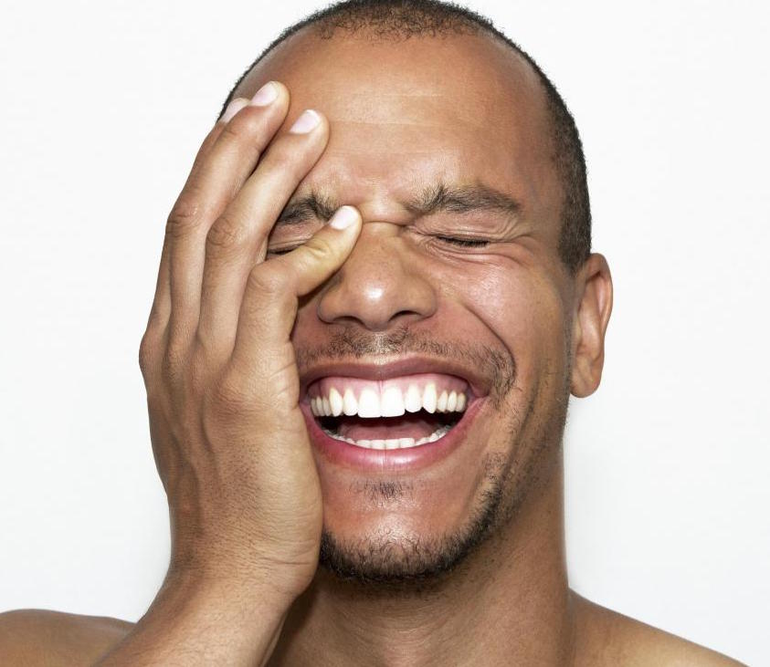 man laughing with his hand to his face