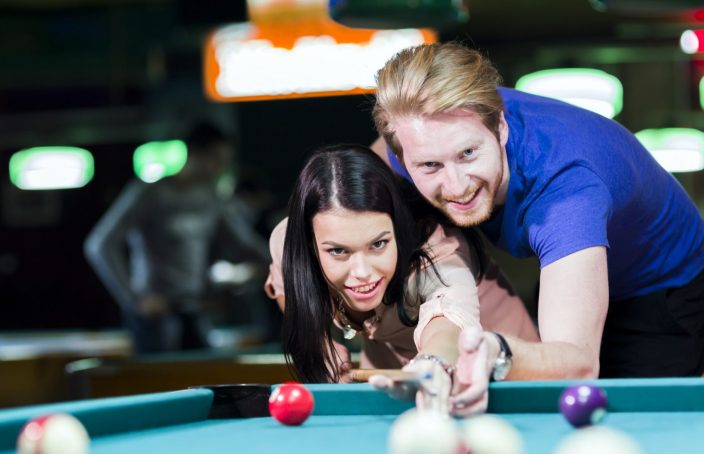 Man teaching a woman how to play pool