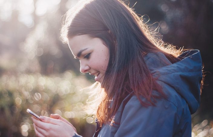 girl checking her phone outside